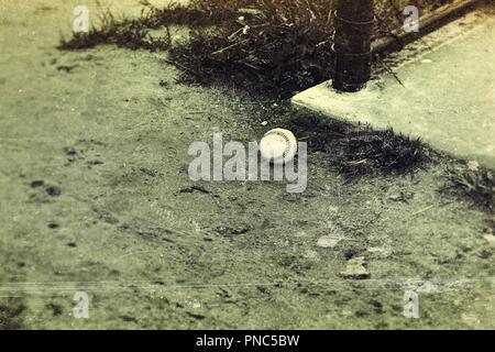 Experimental Edit: A lone baseball sits next to the dugout on a baseball field Stock Photo