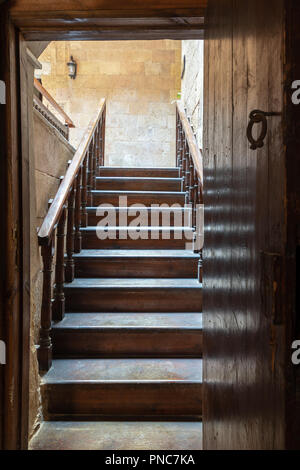 Open wooden door revealing wooden old staircase going up with with reflections of the stairs on the door located at the House of Egyptian Architecture Stock Photo