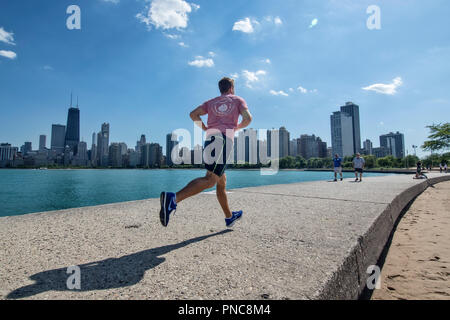 Jogger on North Avenue Beach pier, Lake Michicago, with a view of the Chicago, IL skyline. Stock Photo