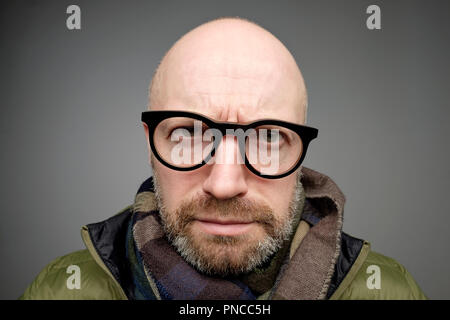 Closeup portrait of european funny bald mature man thinking trying hard to remember something looking confused isolated on gray background. Negative e Stock Photo