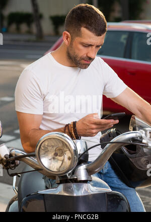 Man with scooter in the city consulting smart phone close up Stock Photo