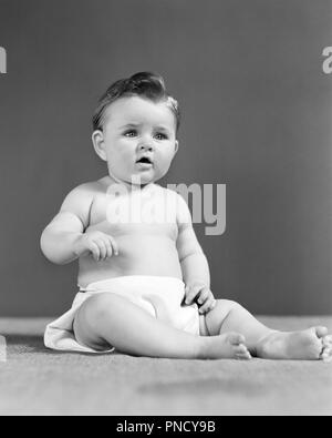 1940s HEALTHY BABY GIRL ONE YEAR OLD SITTING UPRIGHT WEARING CLOTH DIAPER LOOKING AT CAMERA QUIZZICALLY  - b18279 HAR001 HARS JUVENILES ONE YEAR OLD ATTENTIVE BABY GIRL BLACK AND WHITE CAUCASIAN ETHNICITY HAR001 OLD FASHIONED Stock Photo