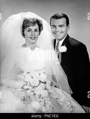1960s PORTRAIT OF HAPPY SMILING BRIDE AND GROOM IN WEDDING CLOTHES LOOKING AT CAMERA - b20909 HAR001 HARS INSPIRATION RISK VEIL SPIRITUALITY CONFIDENCE CEREMONY B&W EYE CONTACT SUIT AND TIE DREAMS HAPPINESS CHEERFUL ADVENTURE CUSTOM COURAGE CHOICE EXCITEMENT TRADITION OCCASION SMILES JOYFUL STYLISH CARNATION MID-ADULT MID-ADULT MAN MID-ADULT WOMAN TOGETHERNESS WIVES BLACK AND WHITE CAUCASIAN ETHNICITY HAR001 OLD FASHIONED Stock Photo
