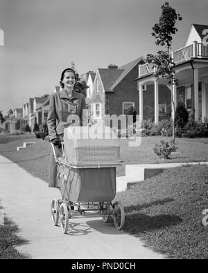 1950s SMILING WOMAN MOTHER WALKING PUSHING BABY CARRIAGE ALONG SUBURBAN SIDEWALK - b6955 HAR001 HARS ACTIVITY HAPPINESS PHYSICAL STRENGTHENING CHEERFUL SELF ESTEEM ALONG PRIDE SMILES MENTAL HEALTH FLEXIBILITY JOYFUL MUSCLES STYLISH BABY CARRIAGES MID-ADULT MID-ADULT WOMAN MOMS RELAXATION BABY CARRIAGE BLACK AND WHITE CAUCASIAN ETHNICITY HAR001 OLD FASHIONED PRAMS Stock Photo