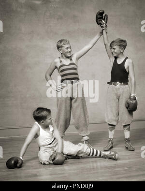1930s TWO BOYS BOXING A THIRD DECLARING ONE THE WINNER THE DEFEATED LOOSER IS SITTING ON THE FLOOR - b8248 HAR001 HARS FITNESS JUVENILE STYLE FEAR HEALTHY REFEREE BALANCE COMPETITION ATHLETE KNICKERS LIFESTYLE SATISFACTION CELEBRATION BROTHERS ATHLETICS FRIENDSHIP FULL-LENGTH PHYSICAL FITNESS WINNER INSPIRATION MALES RISK ATHLETIC SIBLINGS CONFIDENCE B&W GOALS SUCCESS ACTIVITY HAPPINESS PHYSICAL PROTECTION STRENGTH TROUSERS VICTORY COURAGE EXCITEMENT LEADERSHIP PRIDE ON THE AUTHORITY SIBLING THIRD CONCEPTUAL ATHLETES BOXING GLOVES FLEXIBILITY MUSCLES STYLISH DECLARING KNEE PANTS KNICKERBOCKERS Stock Photo