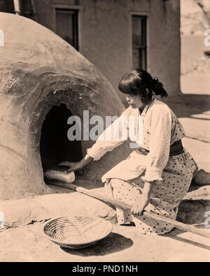 1930s NATIVE AMERICAN WOMAN BAKING BREAD KIVA OVEN SAN ILDEFONSO PUEBLO MEW MEXICO USA - i1562 HAR001 HARS UNITED STATES OF AMERICA CARING B&W NORTH AMERICA NORTH AMERICAN LOAF MEXICO HIGH ANGLE TRADITION NATIVE AMERICAN PUEBLO NATIVE AMERICANS YOUNG ADULT WOMAN BLACK AND WHITE HAR001 ILDEFONSO INDIGENOUS KIVA OLD FASHIONED Stock Photo