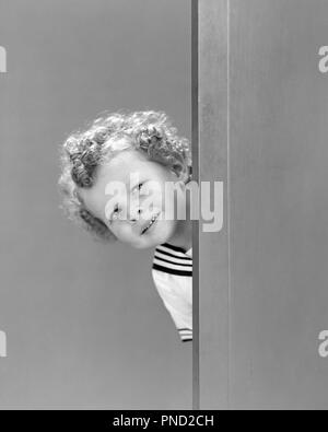 1940s CURLY BLOND HAIR LITTLE BOY IN SAILOR SUIT PEEKING AROUND CORNER LOOKING AT CAMERA - j9220 HAR001 HARS MYSTERY PLEASED JOY LIFESTYLE SAILOR STUDIO SHOT HOME LIFE COPY SPACE MALES CORNER EXPRESSIONS B&W EYE CONTACT HAPPINESS HEAD AND SHOULDERS CHEERFUL DISCOVERY CURLY SMILES CONNECTION CURIOUS JOYFUL STYLISH JUVENILES BLACK AND WHITE CAUCASIAN ETHNICITY HAR001 INQUISITIVE OLD FASHIONED Stock Photo