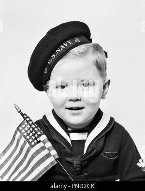 1940s PORTRAIT OF YOUNG BOY WEARING U,S, NAVY CAP AND SAILOR SHIRT HOLDING SMALL AMERICAN FLAG LOOKING AT CAMERA - j9317 HAR001 HARS CELEBRATION WW2 NAVY HEALTHINESS HOME LIFE UNITED STATES COPY SPACE INSPIRATION UNITED STATES OF AMERICA MALES B&W EYE CONTACT FREEDOM HAPPINESS HEAD AND SHOULDERS AND WORLD WARS PRIDE WORLD WAR WORLD WAR TWO WORLD WAR II POLITICS PATRIOTIC STARS AND STRIPES STYLISH WORLD WAR 2 48 STAR BABY BOY USN COOPERATION JUVENILES RED WHITE AND BLUE STARS AND STRIPS BLACK AND WHITE CAUCASIAN ETHNICITY HAR001 OLD FASHIONED Stock Photo