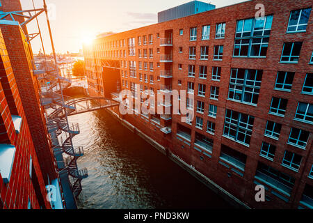 HafenCity canal. Circular staircase, bridge over canal and red brick buildings in the old warehouse district Speicherstadt in Hamburg in golden hour sunset light, Germany. View from above Stock Photo