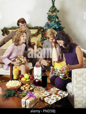 1970s TWO COUPLES EXCHANGING GIFTS AROUND  CHRISTMAS TREE DRINKING WINE SNACKS AND PRESENTS  ON COFFEE TABLE   - kx7355 PHT001 HARS MALES APPLES GIFTS POPCORN SNACKS HAPPINESS AND HOLIDAYS DECEMBER CONNECTION DECEMBER 25 FRIENDLY STYLISH EXCHANGING MID-ADULT MID-ADULT MAN MID-ADULT WOMAN TOGETHERNESS CAUCASIAN ETHNICITY OLD FASHIONED Stock Photo