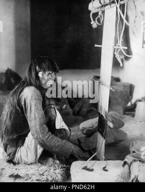 1890s 1898 NATIVE AMERICAN INDIAN MAN LOOKING AT CAMERA WEAVING CEREMONIAL KILT ON LOOM  - q73416 CPC001 HARS PRECISION WEAVE WEAVING YOUNG ADULT MAN BANGS BLACK AND WHITE CEREMONIAL KILT LOOM OLD FASHIONED WEAVER Stock Photo