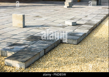 Laying gray concrete paving slabs in house courtyard driveway patio. Professional workers bricklayers are installing new tiles or slabs for driveway,  Stock Photo