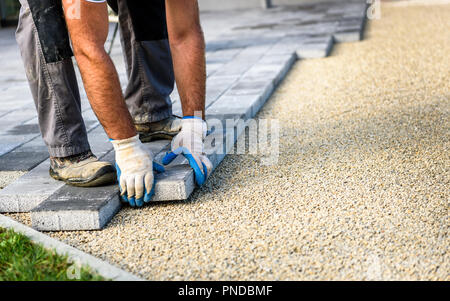 Laying gray concrete paving slabs in house courtyard driveway patio. Professional workers bricklayers are installing new tiles or slabs for driveway,  Stock Photo