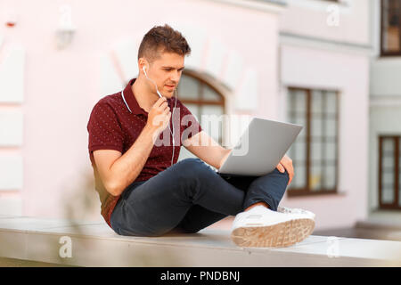 Handsome businessman with laptop talking on microphone in city, Freelancer working and traveling Stock Photo