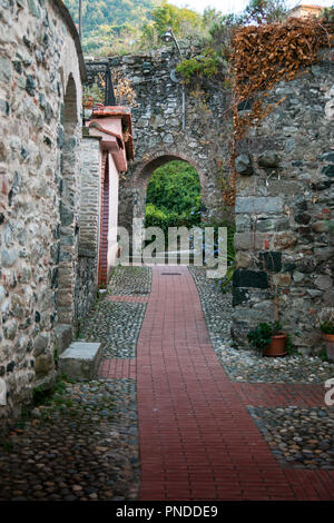 narrow medieval alley or path, with ruined brick walls and a arch, in the town of Levanto, Liguria, northern Italy. Stock Photo