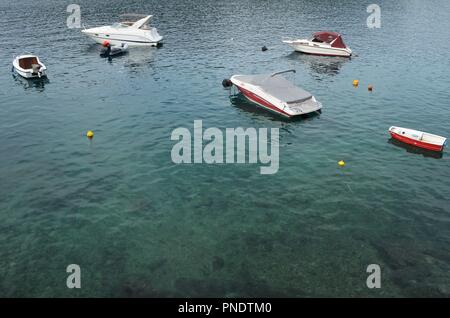 small boats floating in beautiful turquoise and cyan colored water in Rabac in Croatia Stock Photo