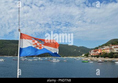 blue, white and red flag of Croatia blowing in the wind near to the Croation coastline in the summer Stock Photo
