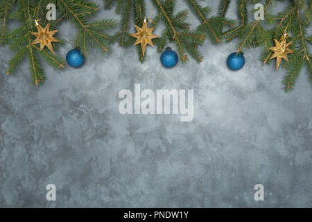 Holiday frame of Christmas decorations on blue dark stucco concrete background with fir branch, gold balls, stars, Christmas socks and toys. Stock Photo