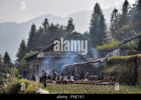 GUIZHOU PROVINCE, CHINA – CIRCA DECEMBER 2017:  A home-made pig-slaughtering on the occasion of wedding feast. An old wooden cottage and misty mountai Stock Photo