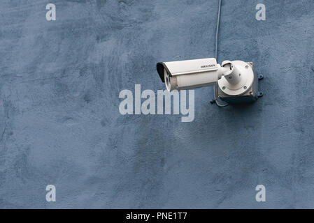 A Hikvision video surveillance camera mounted on a blue exterior wall of a building. Stock Photo