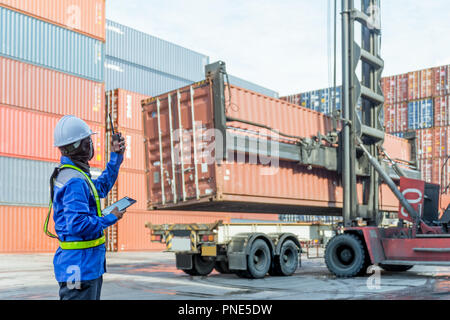 Foreman control loading Containers box from Cargo freight ship for logistics import export background. Stock Photo