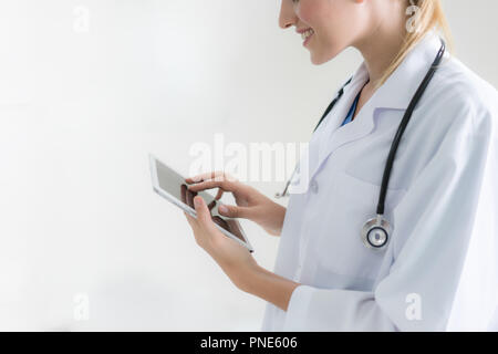 Woman doctor using tablet computer while sitting. Reflecting glass table is a working place of physician. Healthcare, insurance and medicine concept. Stock Photo