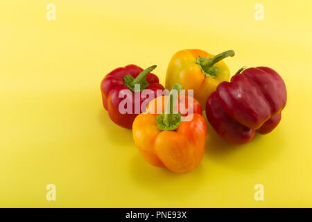 Sweet bellpeppers. Two red and two yellow-orange sweet bellpeppers on a yellow-lemon background. Studio light. Top view Stock Photo