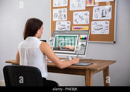 Female Designer Using Graphic Tablet While Working On Computer Stock Photo