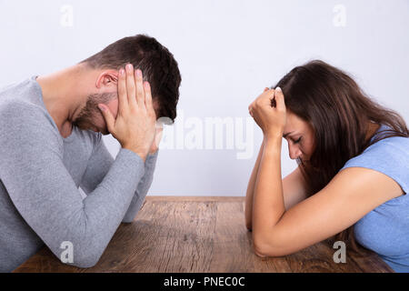 Side View Of A Depressed Young Couple Sitting Opposite Each Other Stock Photo