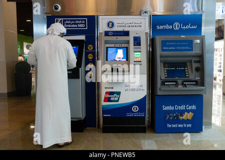 Emirati man using cash ATM machine in Dubai, UAE Stock Photo