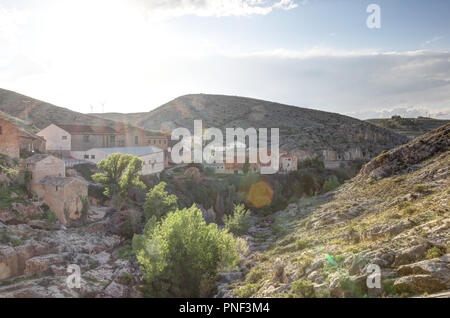 A landscape at the sunset of the rural country town of Almonacid de la Cuba, in Spain, with houses on a small rocky valley with the Rio Aguavivas Stock Photo