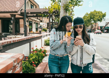 pretty girls discussing something on the phone while walking down the sidewalk in the town. Stock Photo