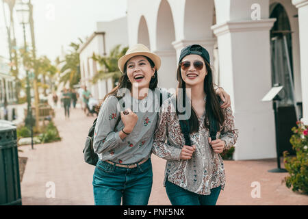 close friends cuddling and laughing cheerfully while taking a trip in the town. Stock Photo