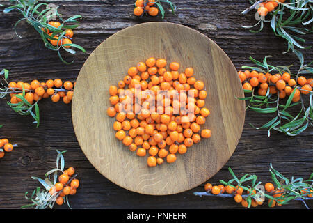 Sea buckthorn background. Organic ripe sea buckthorn on old wooden plate, rustic background. Top view Stock Photo