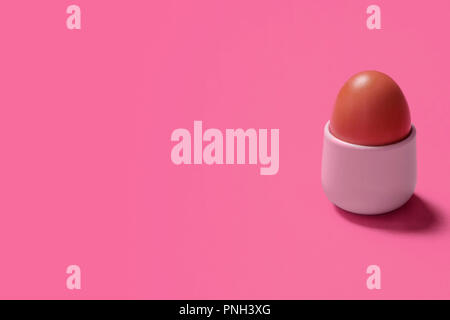 Hard or soft boiled egg in an egg cup on a pink background with space for copy and text Stock Photo