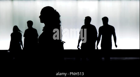 Blurry silhouettes of young  people walking in motion blur in front of the modern building in the night Stock Photo