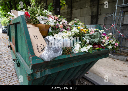 A dumpster filled with discarded flower arrangements that were left behind on graves from visitors at the Père Lachaise Cemetery, Paris, France on a c Stock Photo