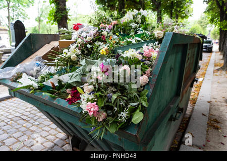 A dumpster filled with discarded flower arrangements that were left behind on graves from visitors at the Père Lachaise Cemetery, Paris, France on a c Stock Photo