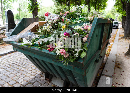 A dumpster filled with discarded flower arrangements that were left behind on graves from visitors at the Père Lachaise Cemetery, Paris, France on a c Stock Photo