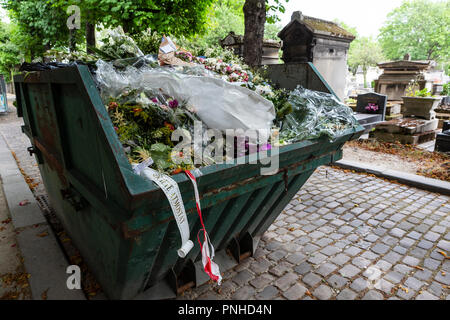 A dumpster filled with discarded flower arrangements that were left behind on graves from visitors at the Père Lachaise Cemetery, Paris, France on a c Stock Photo