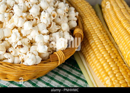 basket with popcorn and fresh fruits of maize on the table close up Stock Photo