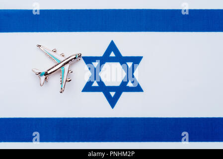 Flag of Israel and the plane. The concept of travel. Toy airplane on the flag of Israel. Stock Photo