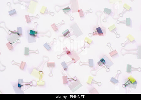Metal binder colorful clips on light background, abstract backdrop for design with text or image, concept of workplace, back to school Stock Photo