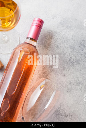 Bottle and glasses of pink rose wine with cork and corkscrew opener on stone kitchen table background. Stock Photo