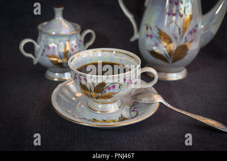 Still life with coffee in a porcelain dish on a dark tablecloth. Stock Photo
