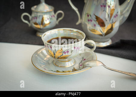 Still life with coffee in a porcelain dish on a dark tablecloth. Stock Photo