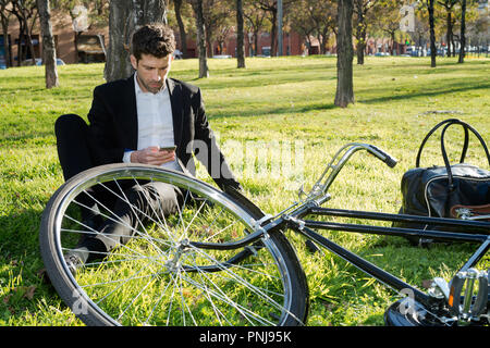 Man with bicycle looks at the telephone in the park Stock Photo