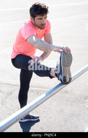 man stretches the leg in metallic bar Stock Photo