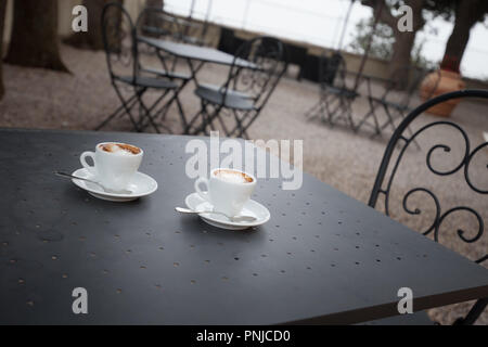 Coffee espresso on metal table in garden outdoor cafe Stock Photo