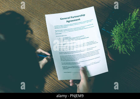 partnership agreement business document signed by a person on the table in office Stock Photo